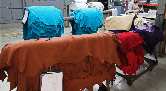 Stacks of colorful leather hides in a factory.