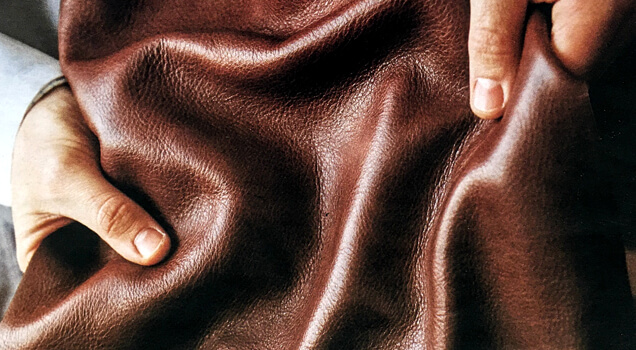 Hands feeling the rich texture of brown leather.
