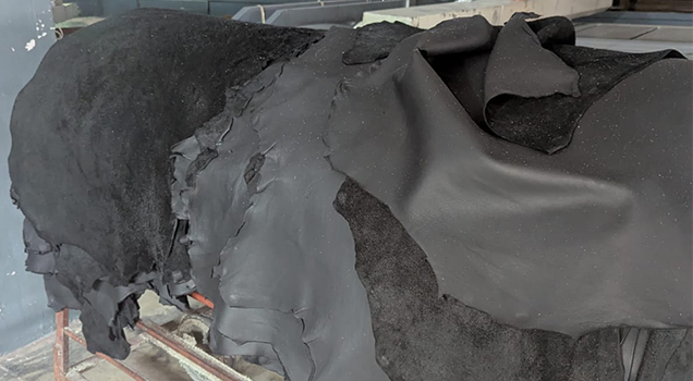 Stack of dark, raw leather hides in a factory.