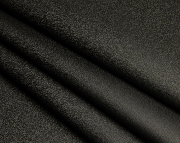 Close-up of smooth, dark grey, or black synthetic leather fabric.